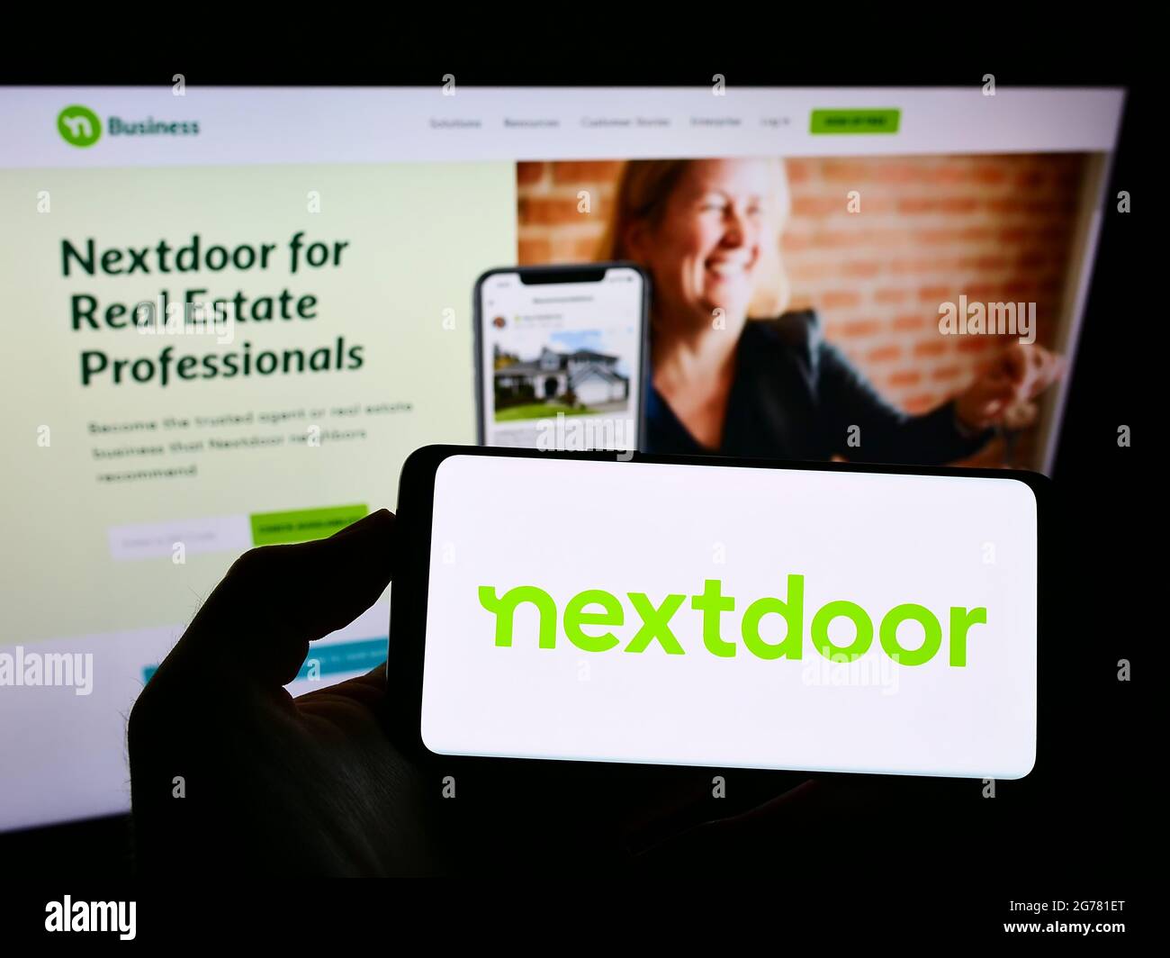 Personne tenant un téléphone portable avec le logo de la société de réseau social américaine nextdoor Inc. À l'écran en face de la page Web d'affaires. Mise au point sur l'affichage du téléphone. Banque D'Images