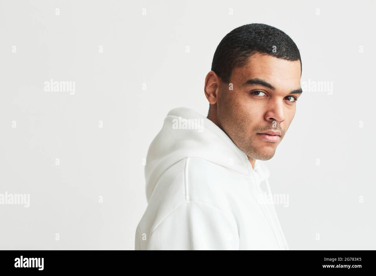 Portrait minimal d'un bel homme latino-américain regardant l'appareil photo portant un espace de copie blanc Banque D'Images
