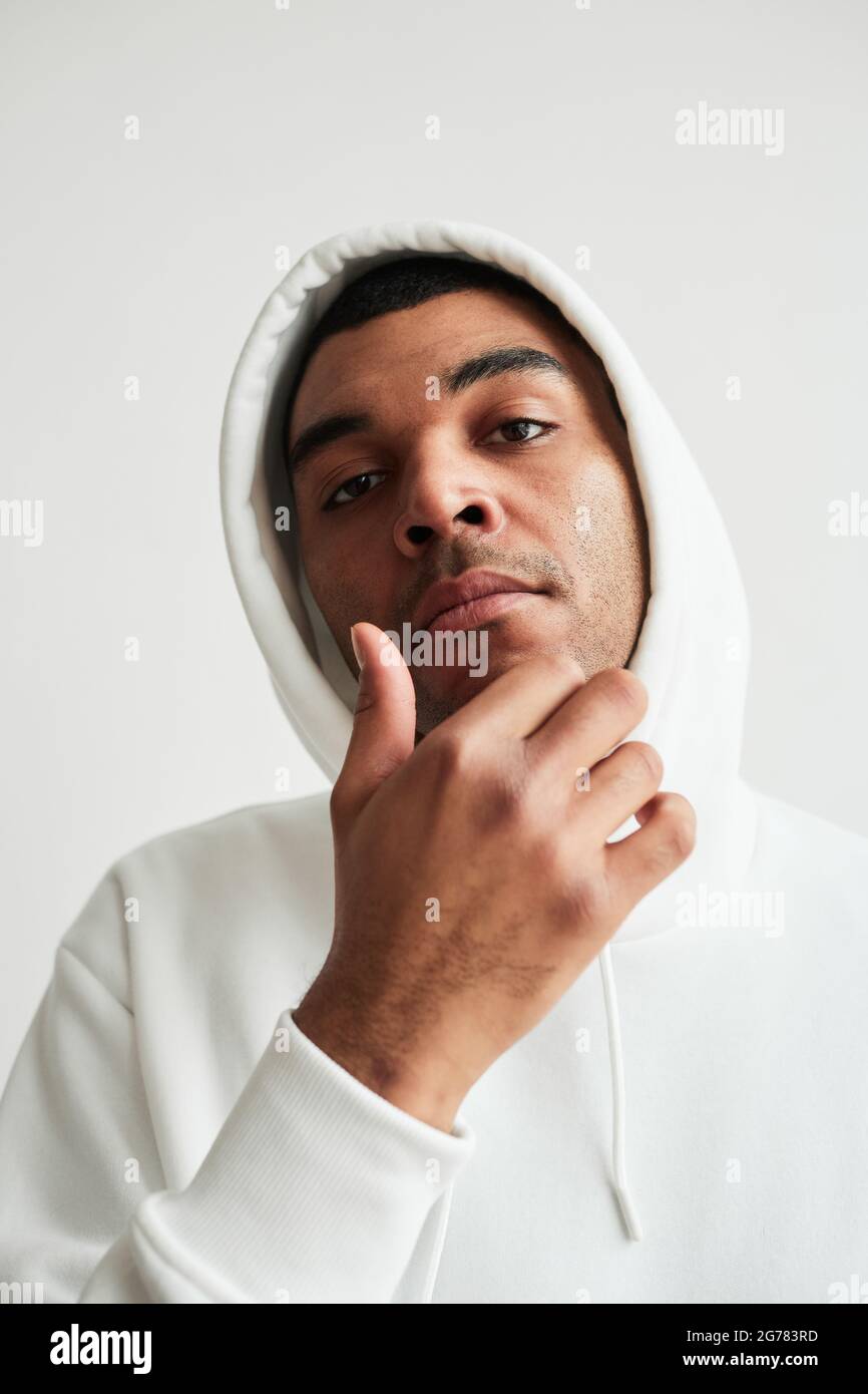 Portrait vertical d'un homme latino-américain robuste portant un sweat à capuche blanc et regardant l'appareil photo Banque D'Images