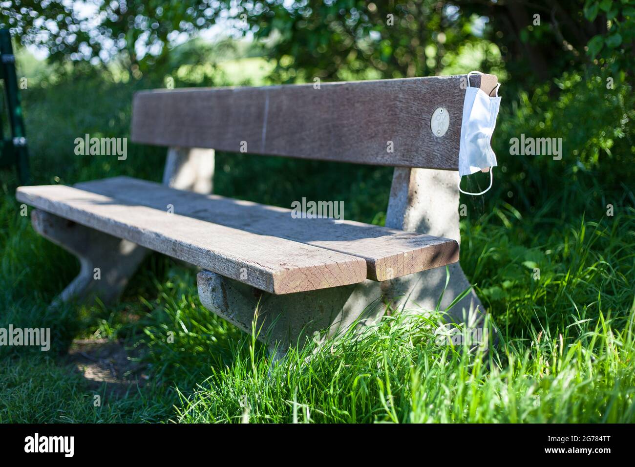 Mise au point sélective d'un masque facial laissé sur un banc en bois dans un parc sous la lumière du soleil Banque D'Images