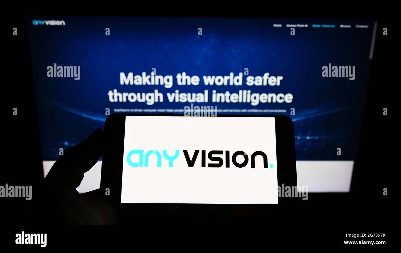 Personne tenant un smartphone avec le logo de la société AnyVision Interactive technologies Ltd. À l'écran devant le site Web. Mise au point sur l'affichage du téléphone. Banque D'Images