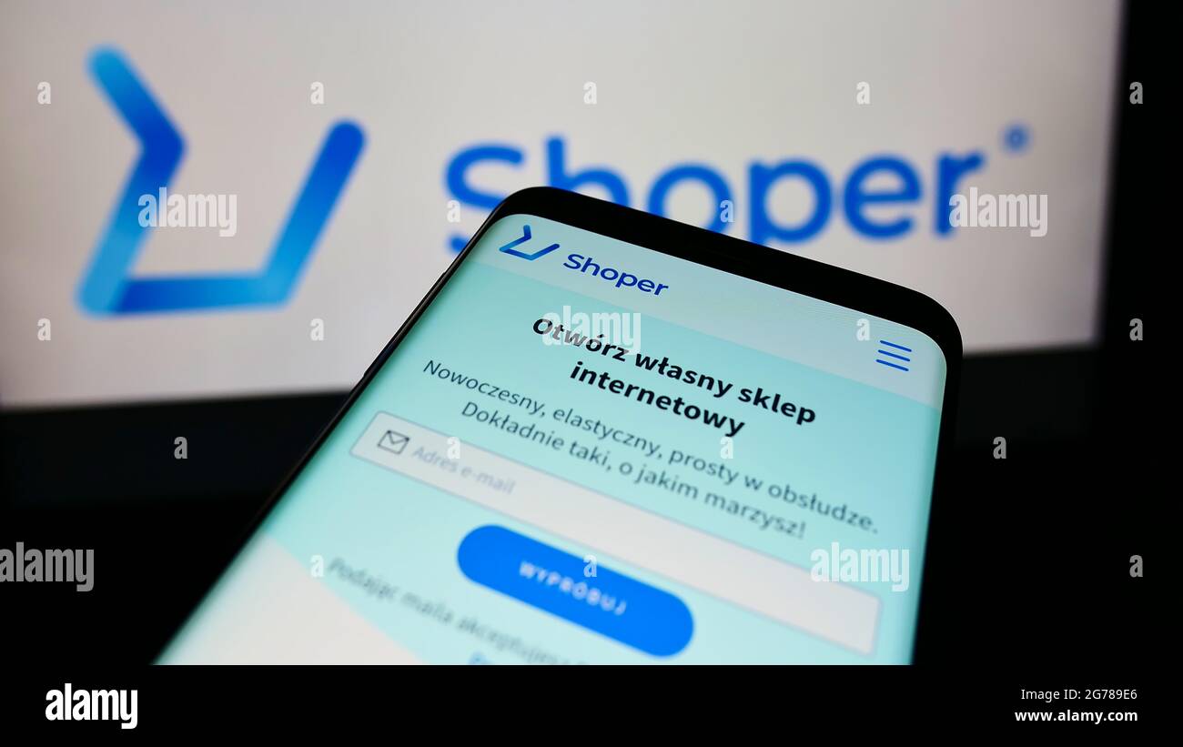 Téléphone portable avec page web de la société polonaise de logiciels de commerce électronique Shopper S.A. à l'écran devant le logo de l'entreprise. Faites la mise au point dans le coin supérieur gauche de l'écran du téléphone. Banque D'Images
