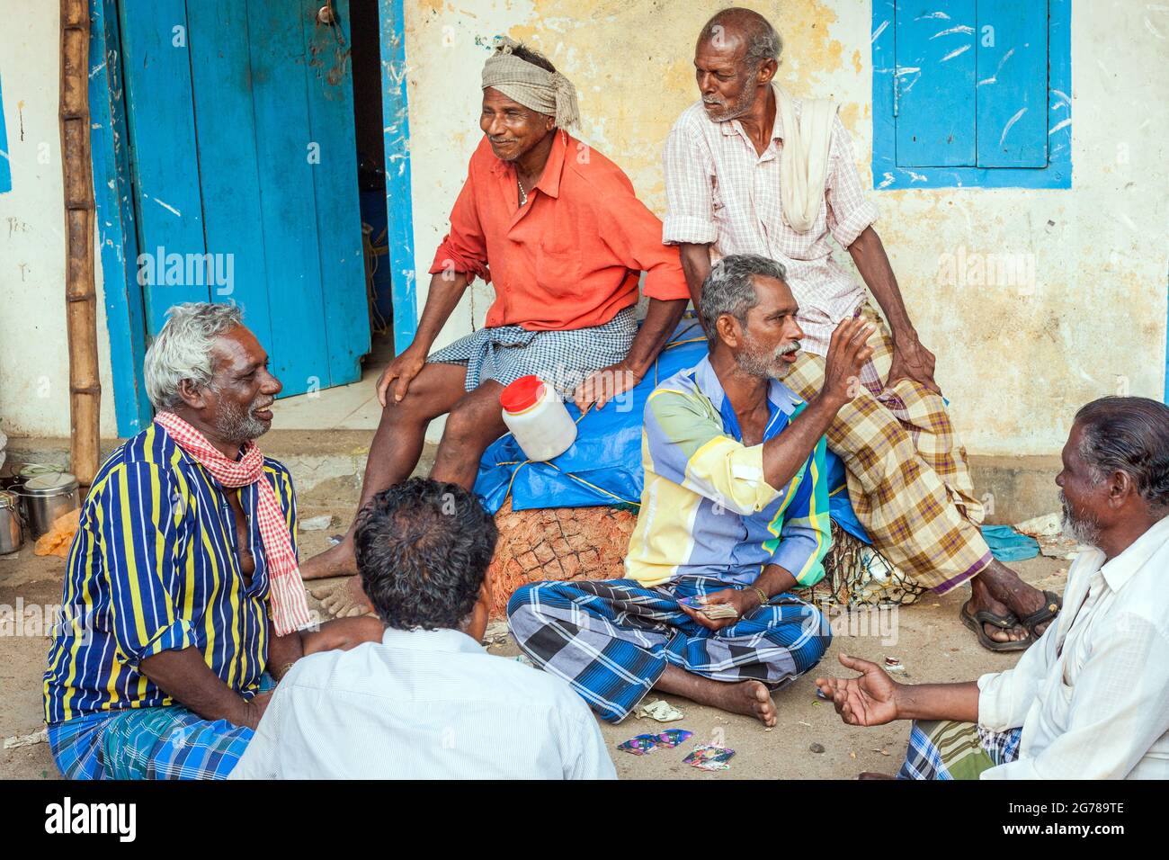 Groupe de pêcheurs hors service assis sur des cartes à jouer au sol, Vizhinjam, Kerala, Inde Banque D'Images