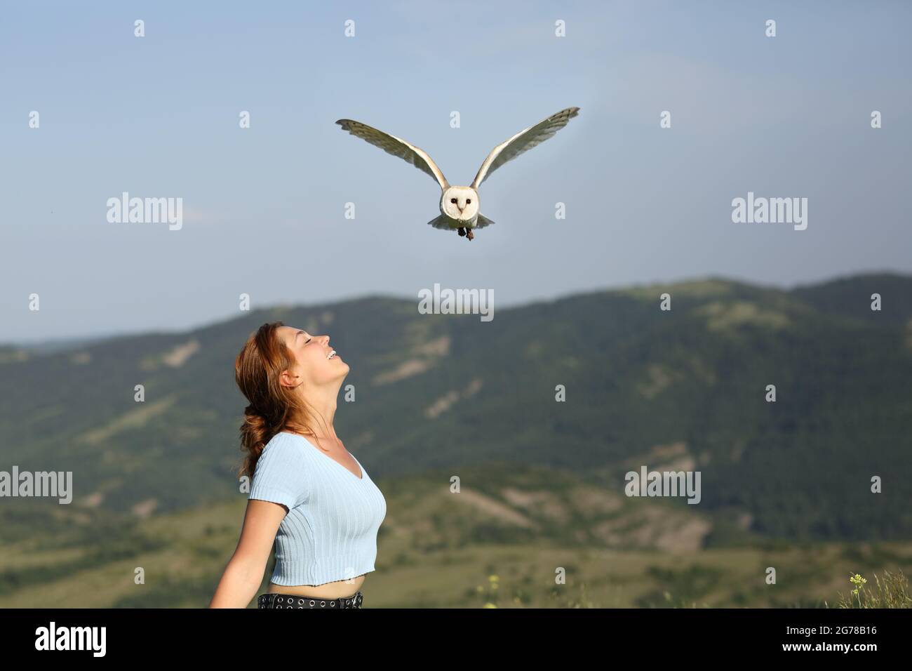 Profil d'une femme heureuse respirant de l'air frais dans la nature et un hibou volant au-dessus Banque D'Images