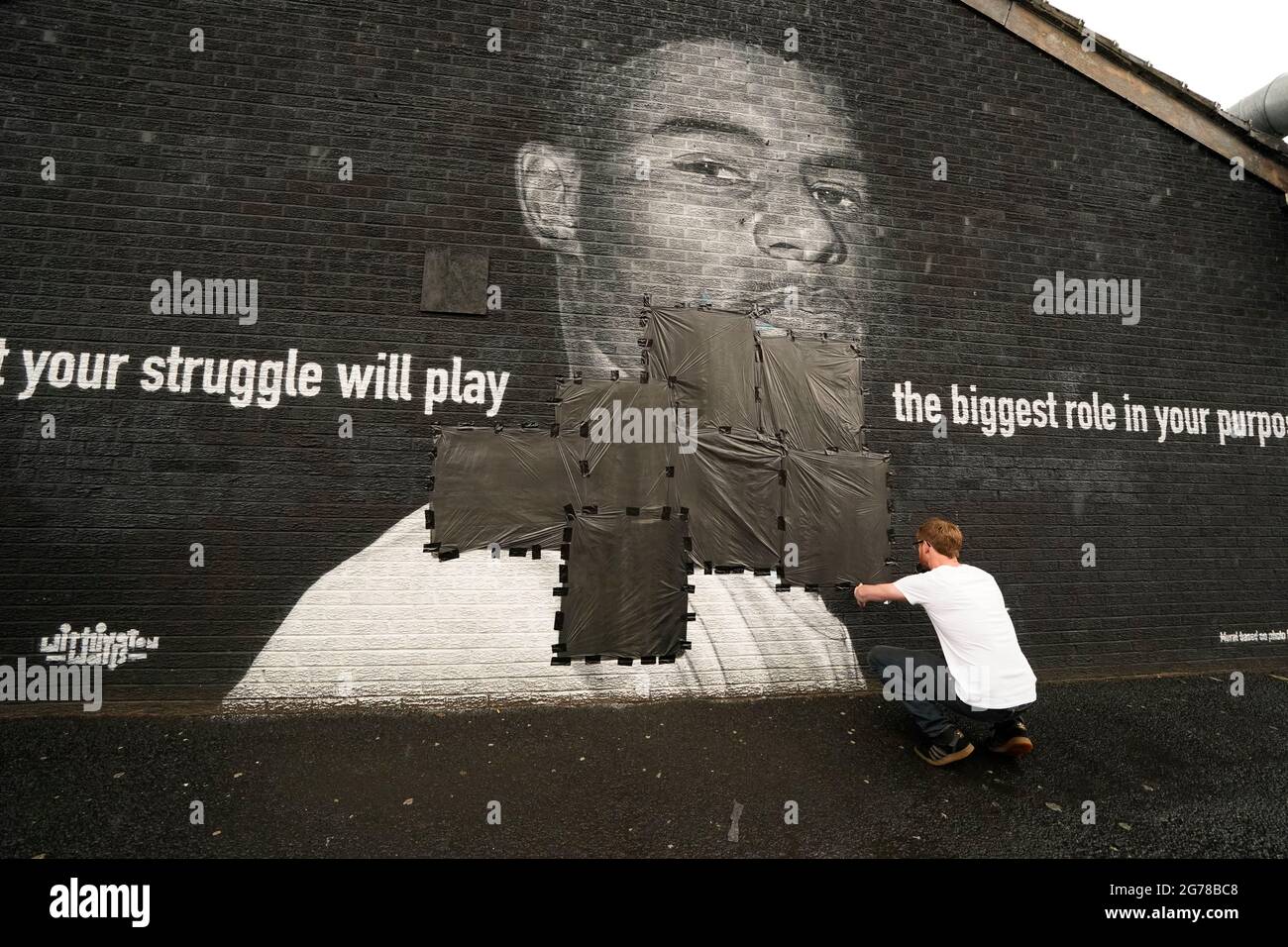 Ed Wellard, de Withington, fait passer des bandes-poubelles sur des textes offensifs sur la fresque de l'attaquant de Manchester United et du joueur d'Angleterre Marcus Rashford sur le mur du Coffee House Cafe sur Copson Street, Withington, qui semblait vandalisé le matin après que l'équipe de football d'Angleterre ait perdu la finale de l'UEFA Euro 2021. Date de la photo: Lundi 12 juillet 2021. Banque D'Images