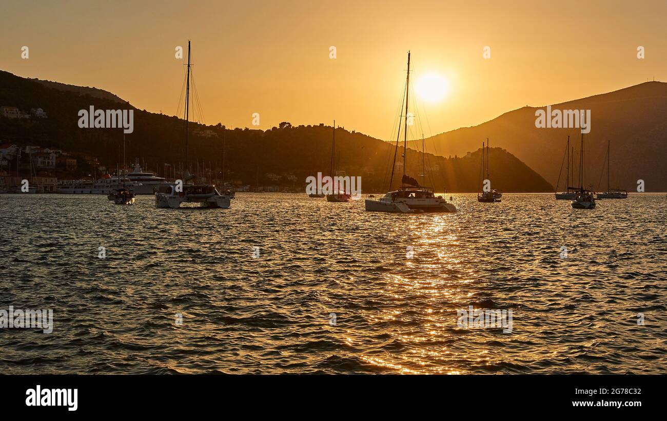 Iles Ioniennes, Ithaka, Baie de Molos, Vathi, crépuscule, Coucher de soleil, vue de Vathi sur la baie avec des bateaux à voile, soleil sur les collines, ciel couleur sable, mer légèrement mouvante Banque D'Images