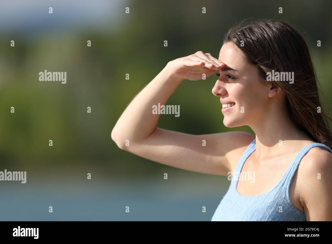 Bonne femme regardant loin de protéger du soleil avec la main sur le front dans un lac Banque D'Images