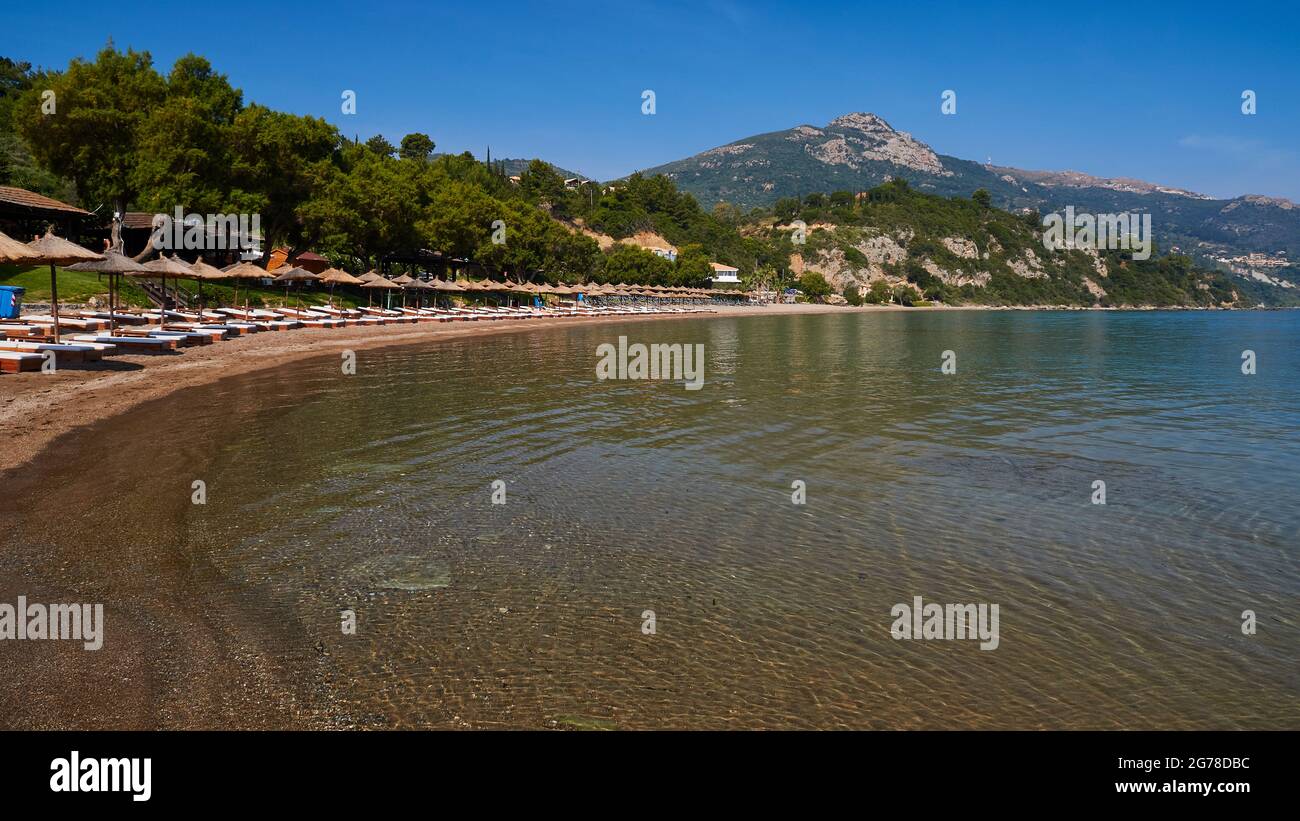 Îles Ioniennes, Zakynthos, au sud de la ville de Zakynthos, plage de Banana, baie semi-circulaire, plage de sable, chaises longues bordées de parasols, mer vert-bleu, ciel bleu, montagne en arrière-plan Banque D'Images