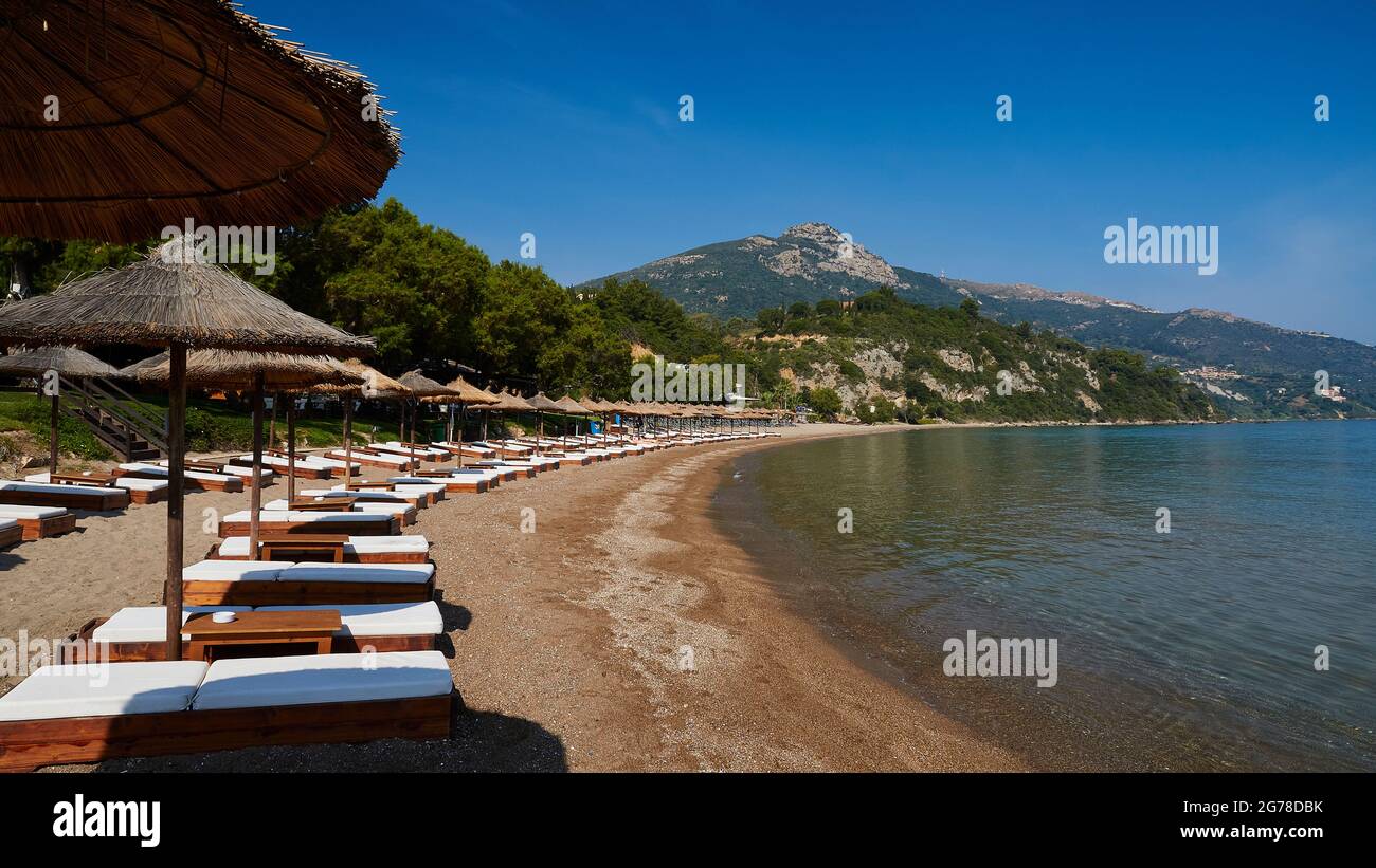 Îles Ioniennes, Zakynthos, au sud de la ville de Zakynthos, plage de Banana, baie semi-circulaire, plage de sable, chaises longues bordées de parasols, mer vert-bleu, ciel bleu, montagne en arrière-plan Banque D'Images