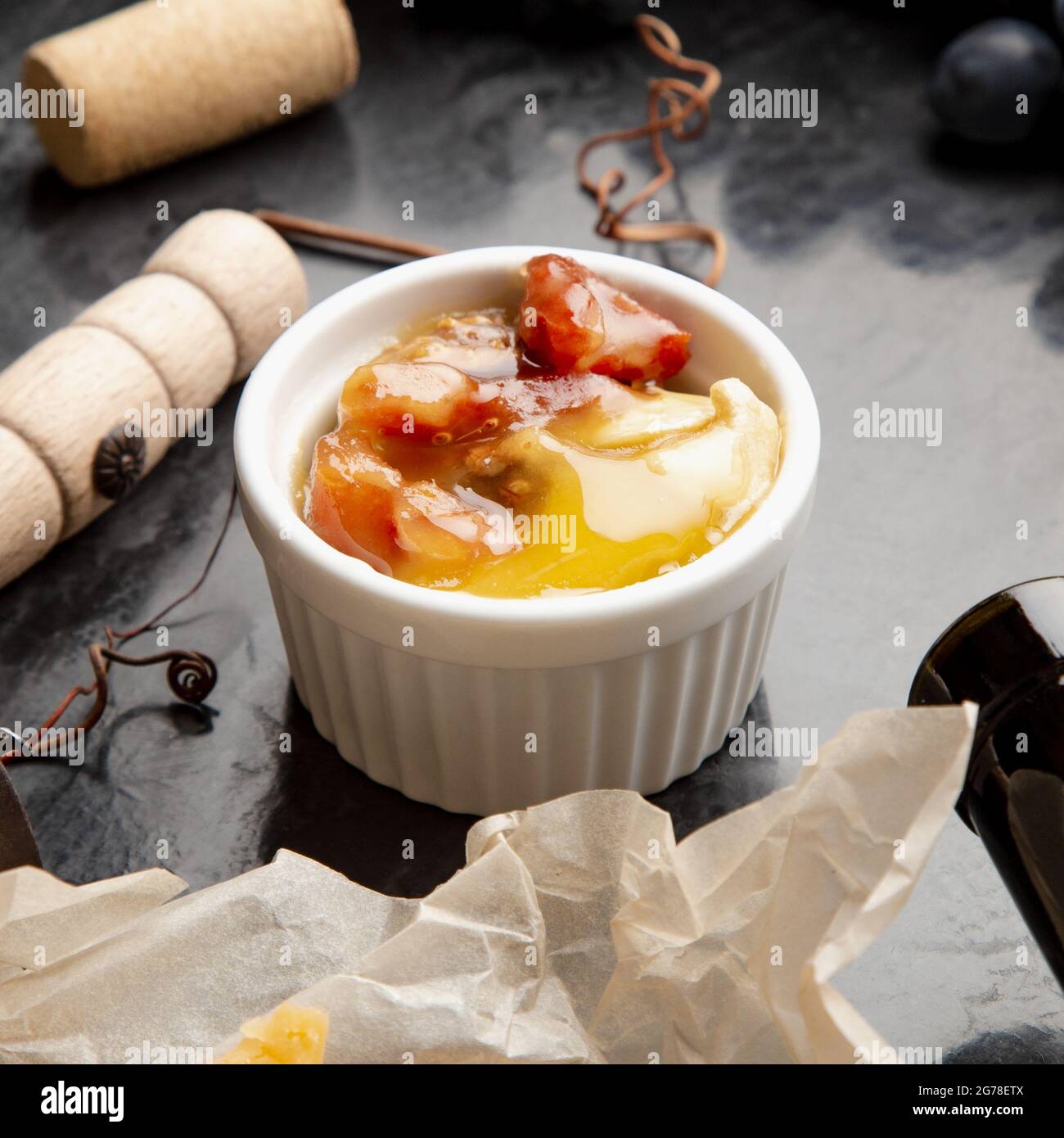 Miel dans un pot sur une table en pierre foncée avec un tire-bouchon au fromage à vin dans un cadre de raisin noir juteux. Délicieux miel d'abeille jaune mélangé avec des noix et des fruits secs Banque D'Images