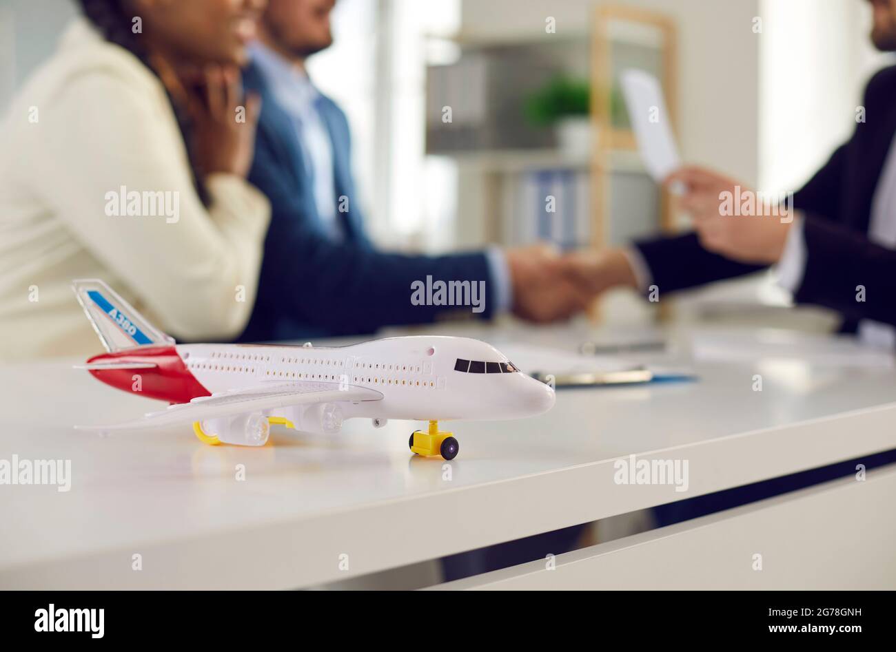 Gros plan du petit avion modèle sur la table sur le fond du couple heureux dans le bureau de l'agence de voyage. Banque D'Images