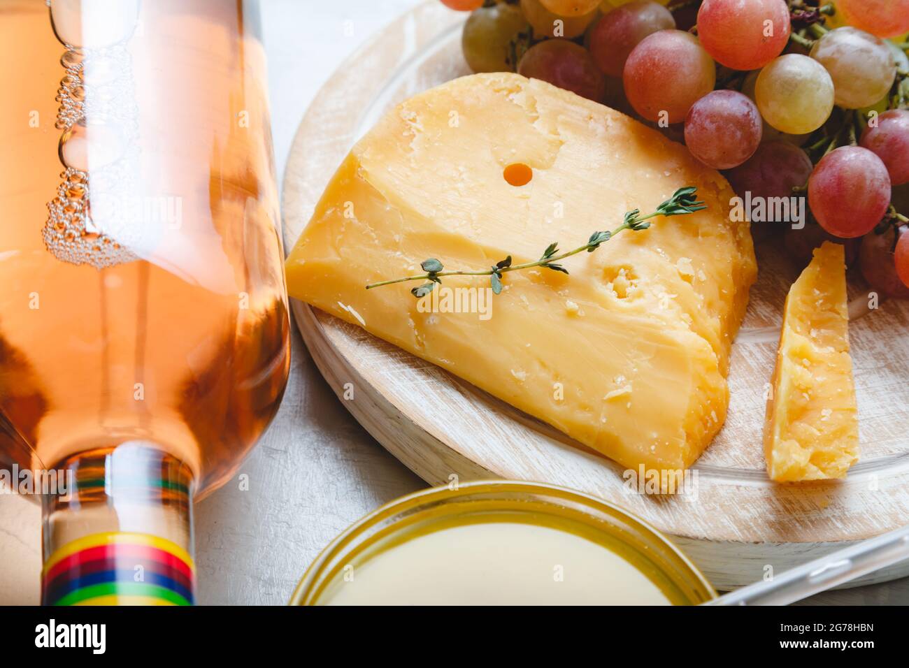 Fromage gouda hollandais vieilli sur la planche à fromage avec des herbes de cumin sur la table. Cheddar aux raisins, vin rose, miel. En-cas au fromage au vin pour un séjour romantique Banque D'Images
