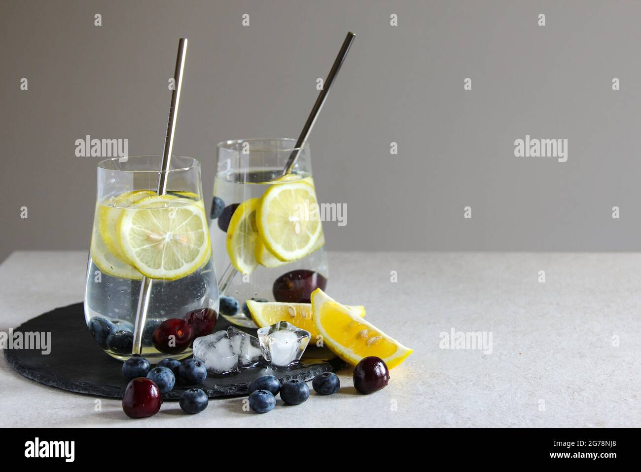 Boissons froides en petites bouteilles. Cerises et limonade au citron ou cocktail. Banque D'Images