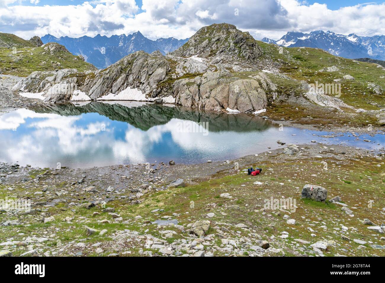 Europe, Autriche, Tyrol, Verwall, Paznaun,Galtür, Friedrichshafener Hut, randonneur de montagne se détend sur un lac de montagne ensoleillé en face de la toile de fond du groupe Silvretta Banque D'Images