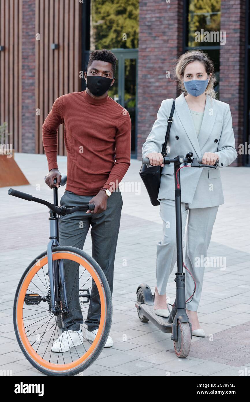 Homme africain et femme caucasienne avec des scooters portant des masques de protection Banque D'Images