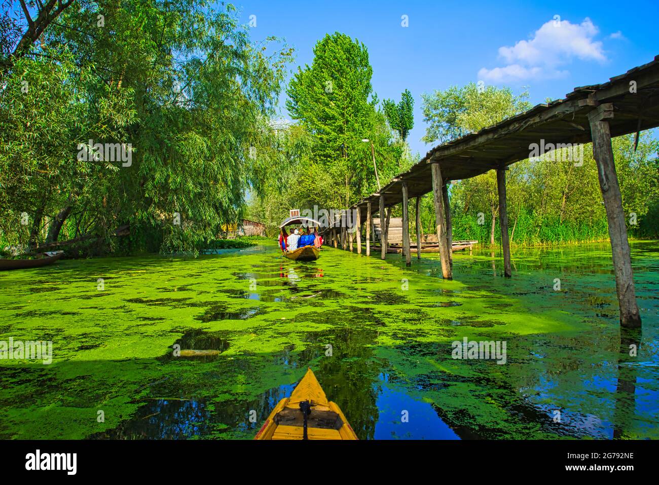 Personnes conduisant des bateaux shikara, naviguant sur la rivière. Un pont en bois pour piétons. Vue sur le lac Dal à Srinagar, État du Cachemire, Inde. Juin 2018 Banque D'Images