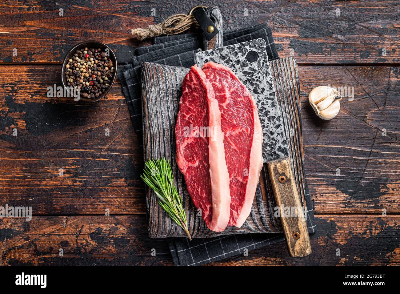Steaks de viande de bœuf sur le dessus de la cicloine crue sur le butboard avec le cale à viande. Arrière-plan sombre. Vue de dessus Banque D'Images
