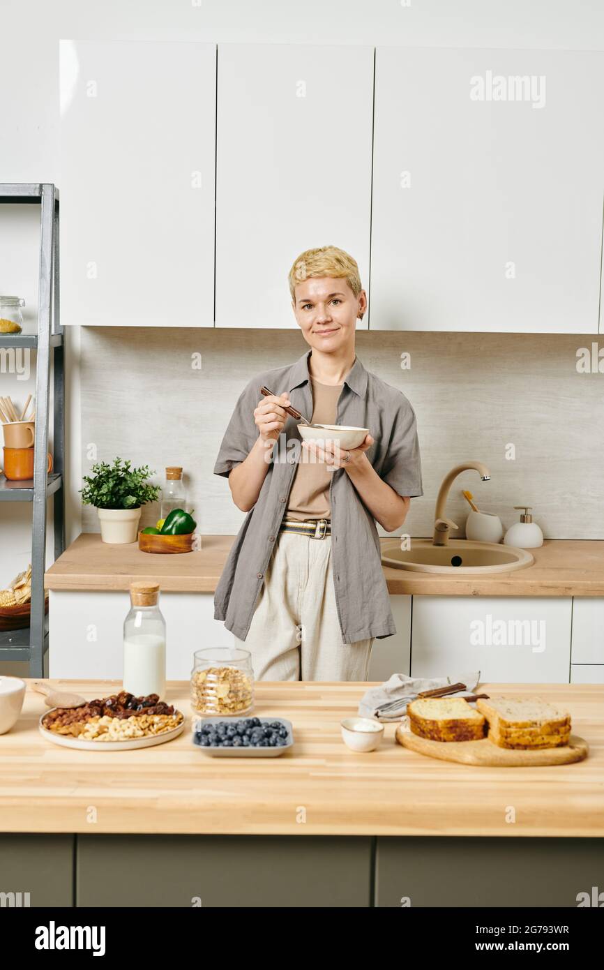 Jeune femme en bonne santé prenant le petit déjeuner devant la table de cuisine Banque D'Images