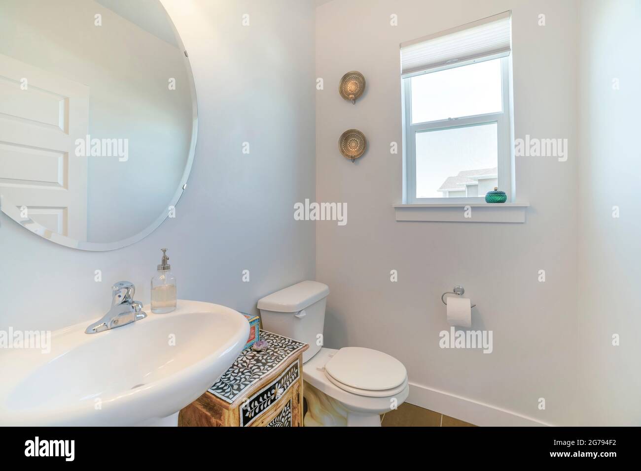 Intérieur d'une salle de bains blanche avec fenêtres, miroir, lavabo et armoire Banque D'Images
