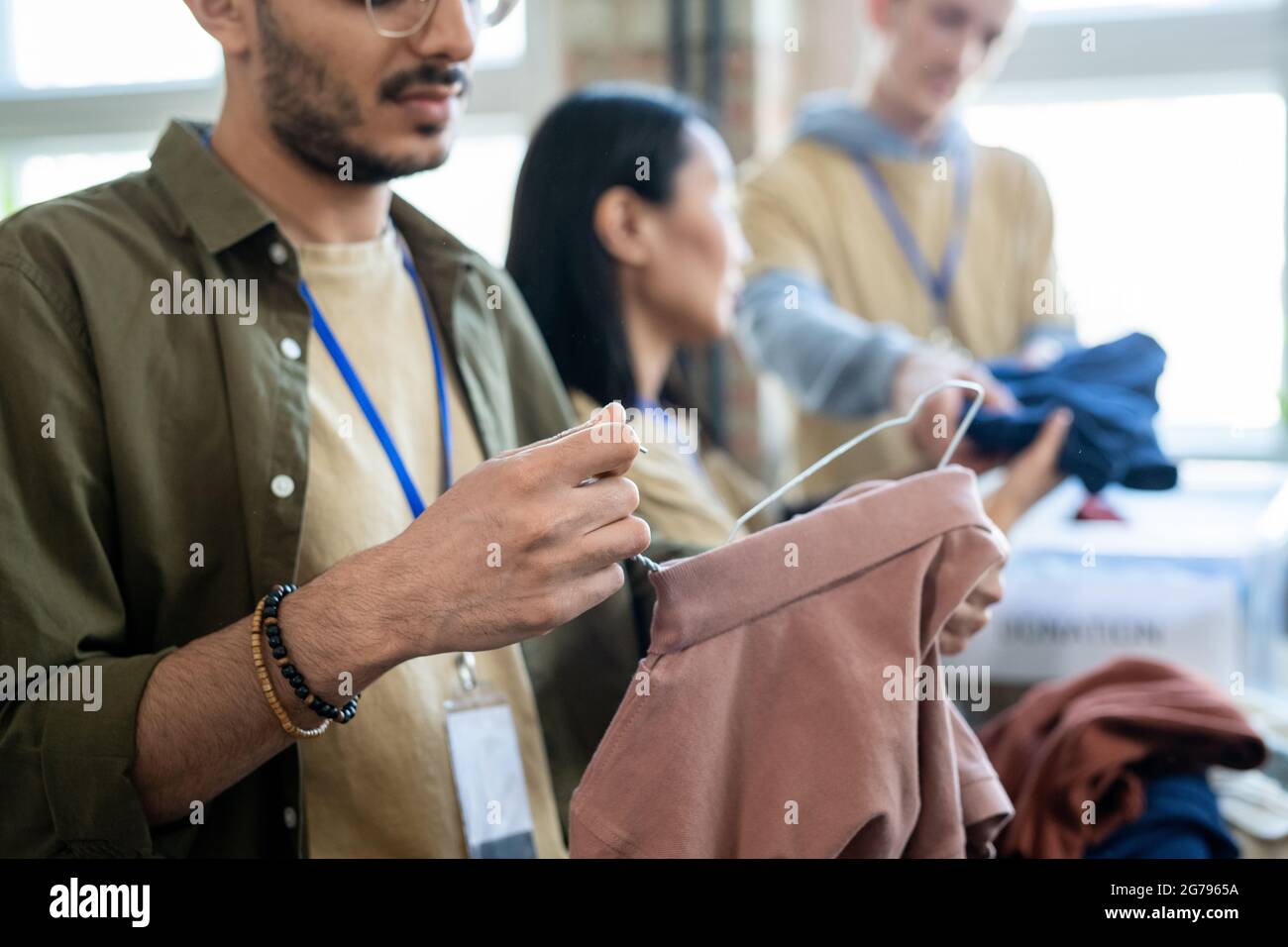 Les jeunes hommes et les autres personnes qui choisissent des vêtements gratuits dans le bureau de bénévolat Banque D'Images