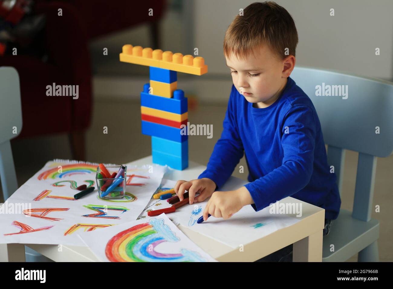 Un garçon de 4-7 ans s'assoit à la table et dessine avec des peintures multicolores. La créativité des enfants. Passe-temps pour les enfants. Photo de haute qualité Banque D'Images
