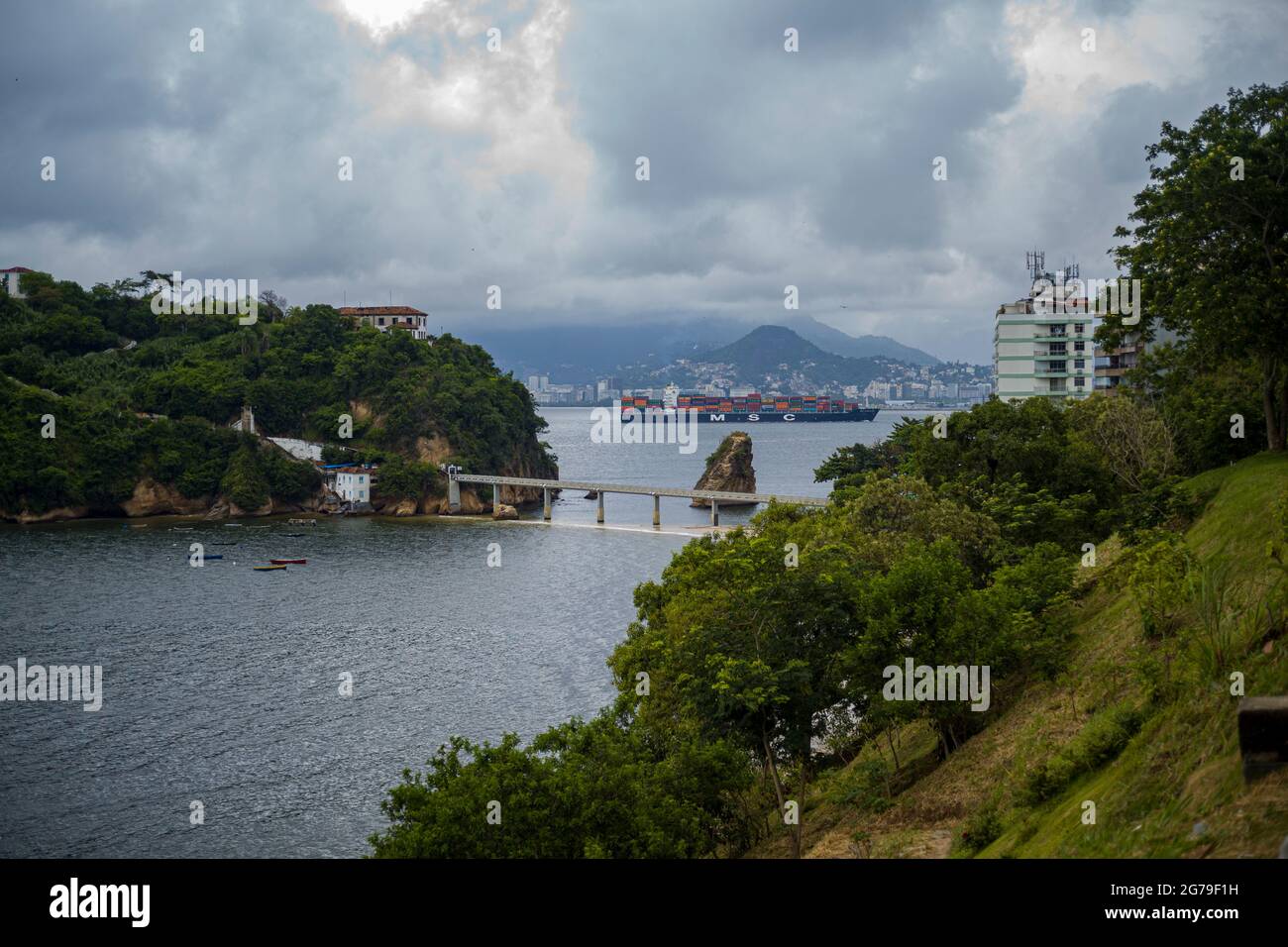 La vue de Ponte da Boa Viagem, Nitreói, Etat de Rio de Janeiro, Brésil. Green Ilha da boa Viagem île privée dans la baie reliée à la terre principale par le pont étroit et le sable jaune sous bleu ciel nuageux. Montagnes à distance. Banque D'Images