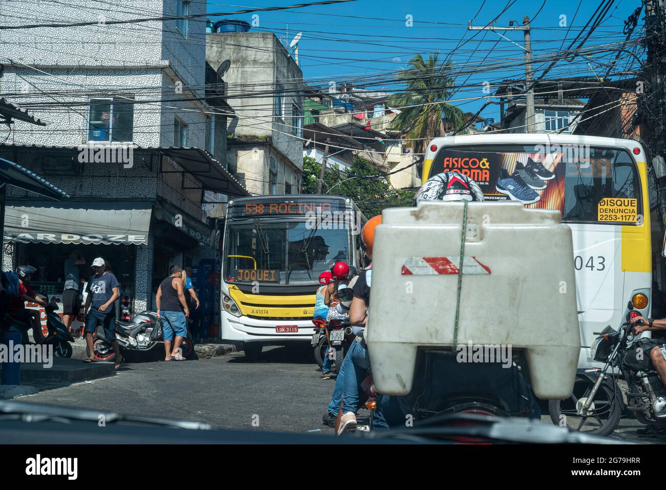 Une vue sur la rue qui donne sur une route avec des scooters et des graffitis sur le mur d'un bâtiment à Rocinha favela, une ville banale ou un bidonville à Rio, Brésil, Amérique du Sud Banque D'Images