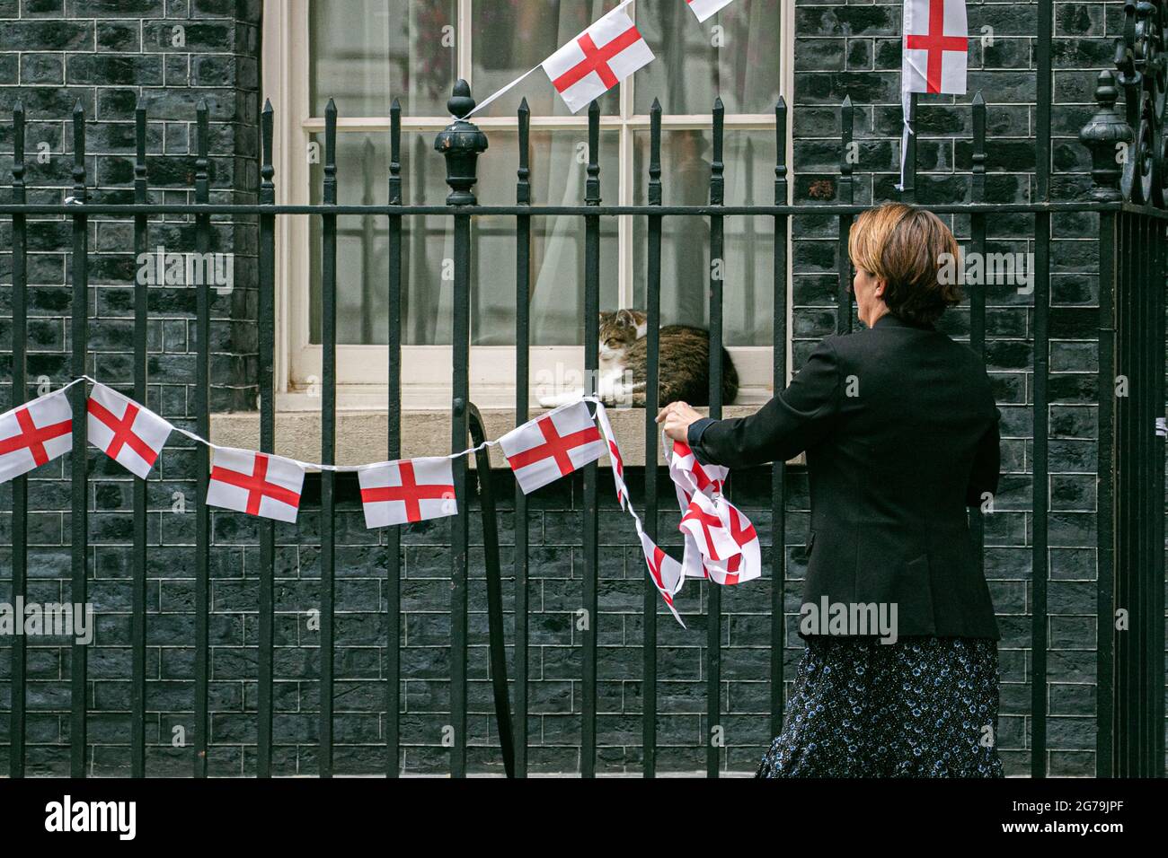 LONDRES 12 juillet 2021. Larry le chat regarde comme un membre du personnel enlève le bunting d'Angleterre attaché aux rails de Downing Street un jour l'équipe nationale de football d'Angleterre avait perdu la finale de l'UEFA Euro 2020 sur des sanctions contre l'Italie à Wembley le dimanche 11 juillet. Les joueurs d'Angleterre Marcus Rashford, Jadon Sancho et Bukayo Saka ont été ciblés sur les médias sociaux avec des abus raciaux après avoir manqué leurs sanctions lors de la fusillade qui a porté la victoire à l'équipe italienne. Credit amer ghazzal/Alamy Live News Banque D'Images