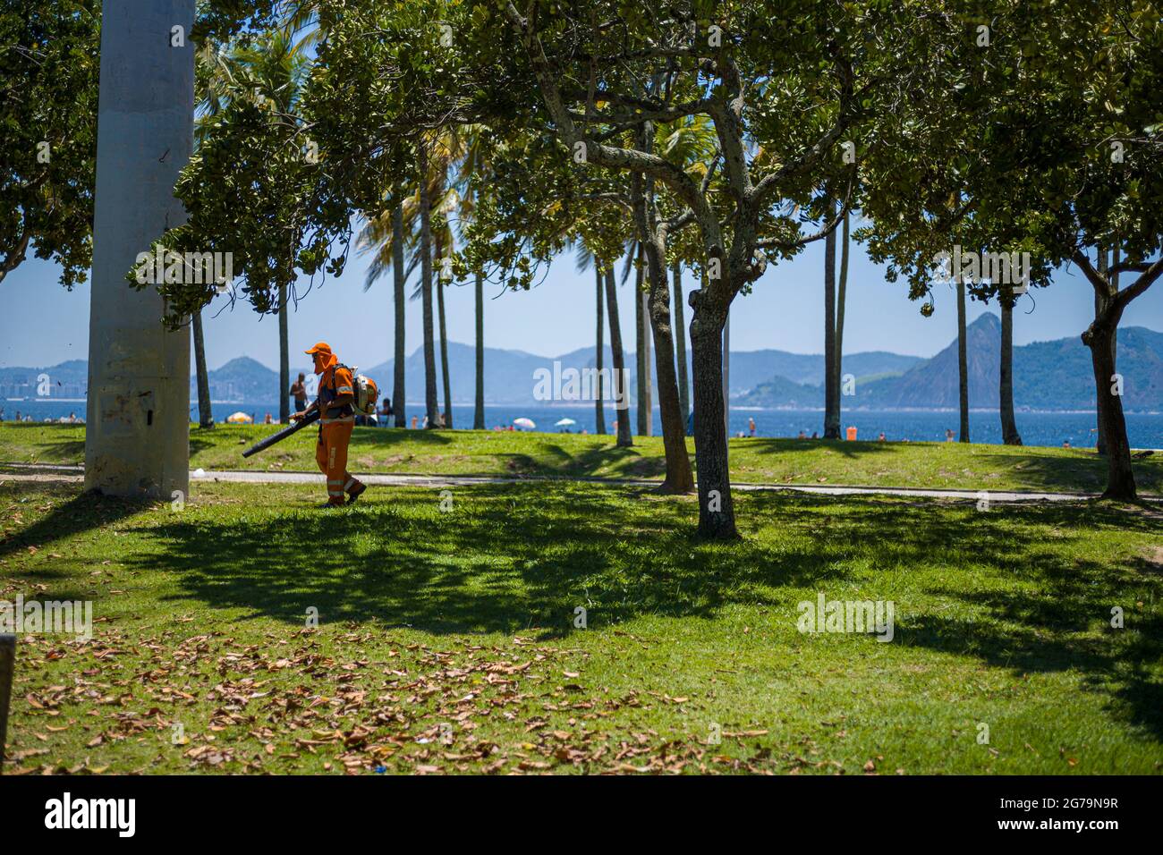 Travailleur utilisant un souffleur de feuilles à usage intensif dans le parc Flamengo - Parque Aterro do Flamengo - à Rio de Janeiro. Un vaste parc en bord de mer avec des terrains de sport, des sentiers de randonnée/cyclisme, un parc de skate et un musée d'art. Banque D'Images