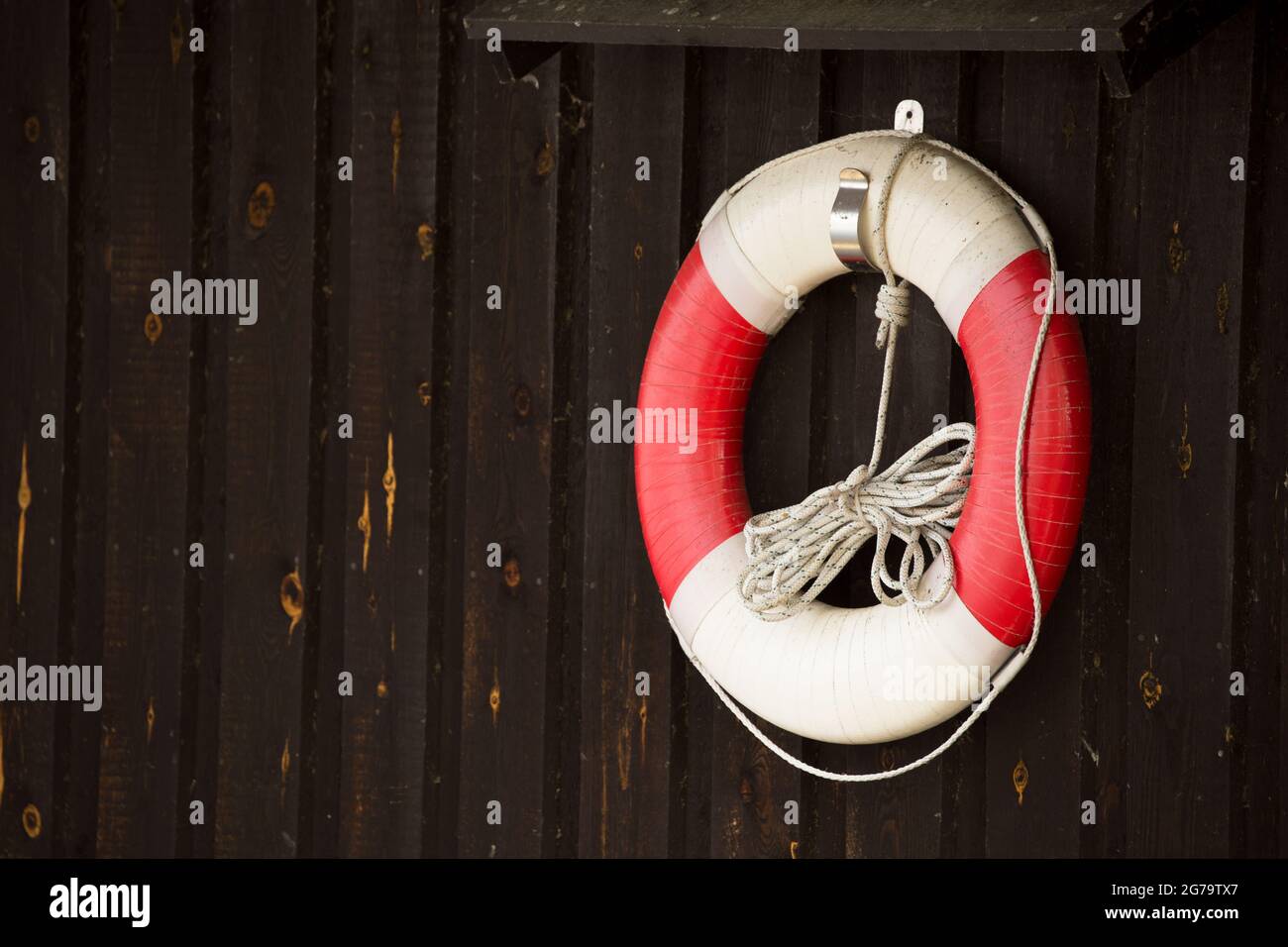 Bouée de sauvetage avec corde flottante accrochée sur un mur en bois sombre  Photo Stock - Alamy