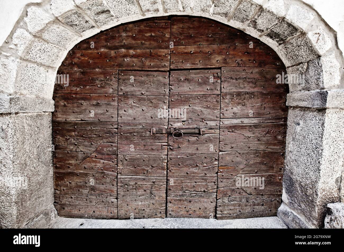Grande porte en bois à deux ailes, à l'intérieur d'une porte en deux ailes, encadrée par une arcades en pierre, Lombardie Banque D'Images