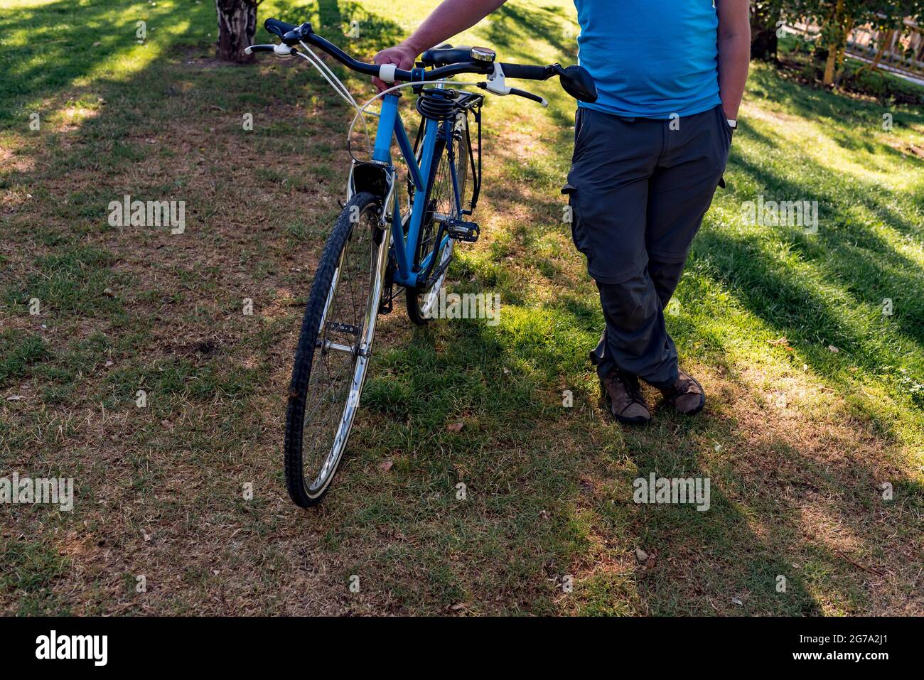 Homme méconnaissable marchant dans le parc avec son vélo Banque D'Images