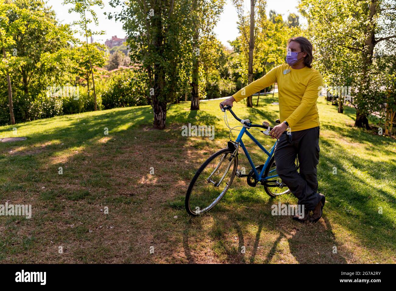 Homme marchant dans le parc avec son vélo Banque D'Images
