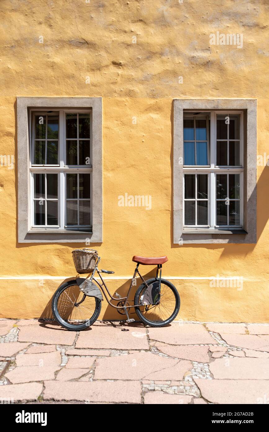 Vélo auto-fabriqué, appuyé contre une façade de maison jaune Banque D'Images