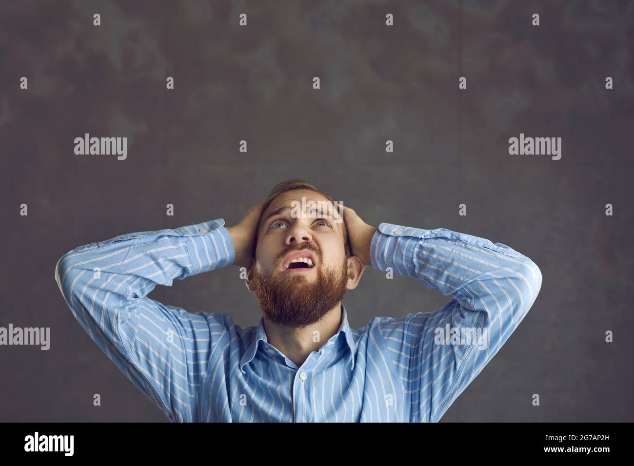 Un homme d'affaires frustré se tenant à la tête avec la main regardant une photo de studio Banque D'Images