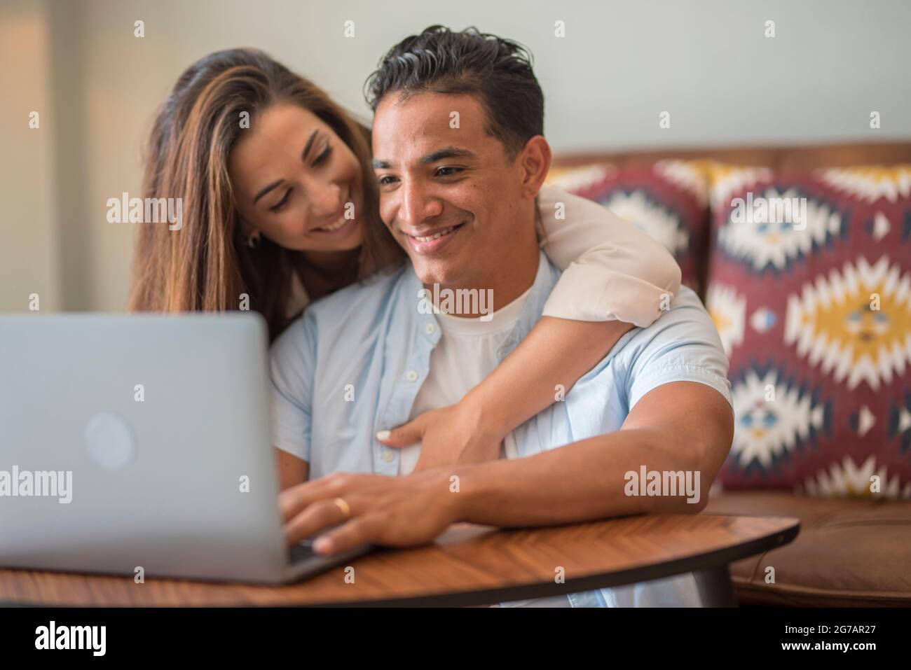Jeune couple interracial se détendant sur un canapé avec ordinateur portable. Les gens dans l'amour et le bonheur de loisirs de style de vie à la maison ensemble - l'homme et la femme aiment l'ordinateur et le travail moderne en ligne Banque D'Images