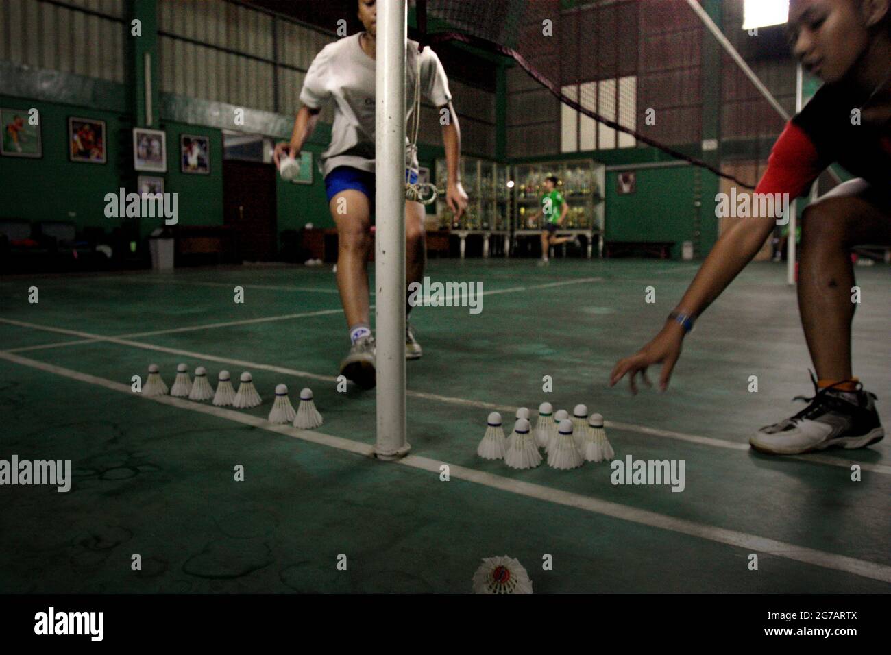Les jeunes joueurs de badminton ont une session d'entraînement au club de badminton Jaya Raya à Jakarta, en Indonésie, photographié dans un fond d'armoire à trophées et une photo de l'ancien joueur vedette du club, Susi Susanti, médaillé d'or olympique. Banque D'Images