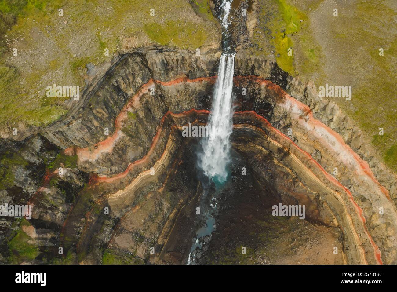 Vue aérienne de haut en bas de la cascade de Hengifoss dans l'est de l'Islande. La troisième plus haute cascade d'Islande est entourée de strates basaltiques avec des couches rouges d'argile entre les couches basaltiques. Banque D'Images