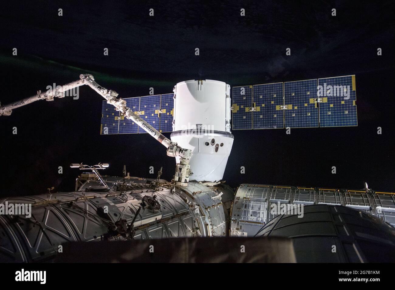 Le SpaceX Dragon est un navire de ravitaillement, avec le bras robotique Canadarm2 d'environ 58 mètres de long au premier plan, représenté installé sur le port terrestre du module Harmony. Une version optimisée et améliorée unique d'une image de la NASA / mandatoty crédit: NASA. Usage éditorial uniquement Banque D'Images