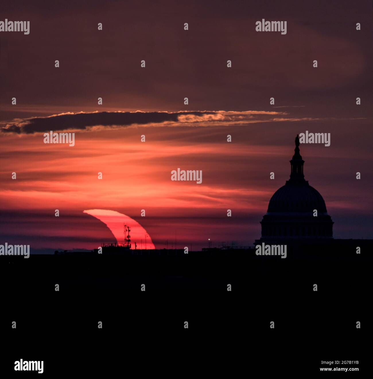 L'éclipse solaire partielle du 10 juin 2021 est vue monter à gauche du bâtiment du Capitole des États-Unis à Washington DC, comme vu d'Arlington, Virginie, États-Unis UNE version unique, optimisée et numériquement améliorée d'une image de la NASA par le photographe senior de la NASA Bill Ingalis / Credit NASA Banque D'Images