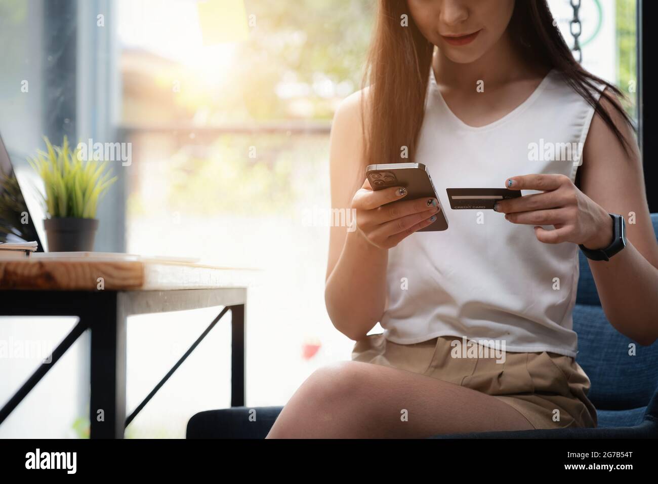 Femme aime avec l'application d'achat en ligne et regardant la carte de crédit pour remplir le numéro de paiement. Banque D'Images