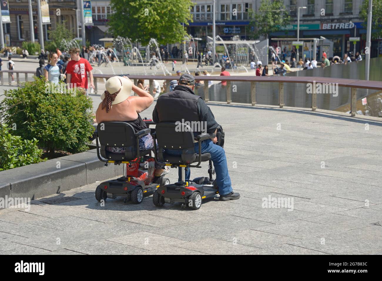 Couple sur les scooters de mobilité, garés côte à côte. Banque D'Images