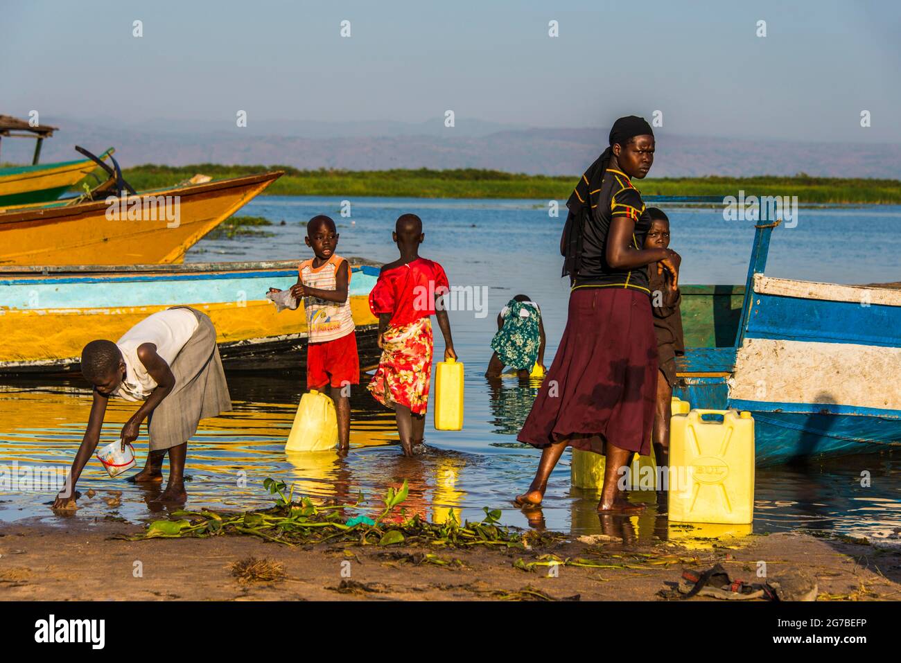 Enfants remplissant de l'eau dans des canisters à Lake Albert, Ouganda, Afrique Banque D'Images