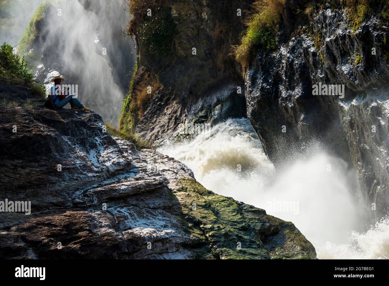 Homme assis au-dessus des chutes de Murchison, également connu sous le nom de chutes de Kabarega sur le Nil, parc national de Murchison Falls, Ouganda, Afrique Banque D'Images