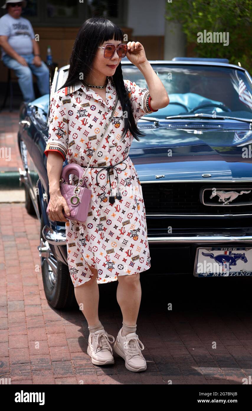 Une femme chinoise qui visite Santa Fe, au Nouveau-Mexique, porte une robe  Louis Vuitton et tient un porte-monnaie Christian Dior lorsqu'elle visite  un spectacle de voitures d'époque Photo Stock - Alamy
