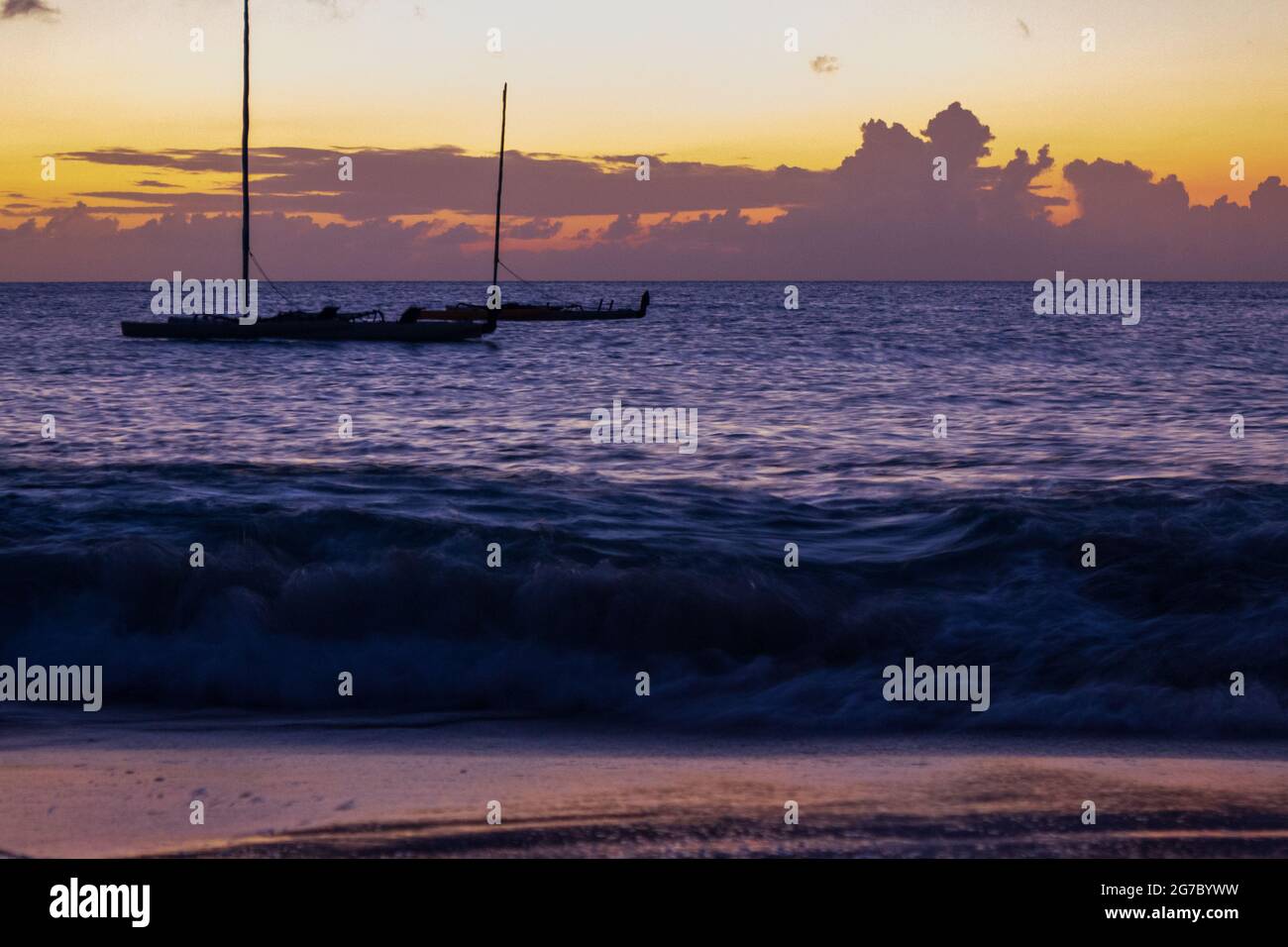 Deux voiliers amarrés dans les Caraïbes au large de la rive près de Frederiksted, Sainte Croix, USVI comme le coucher du soleil se reflète dans les nuages et la mer. Banque D'Images