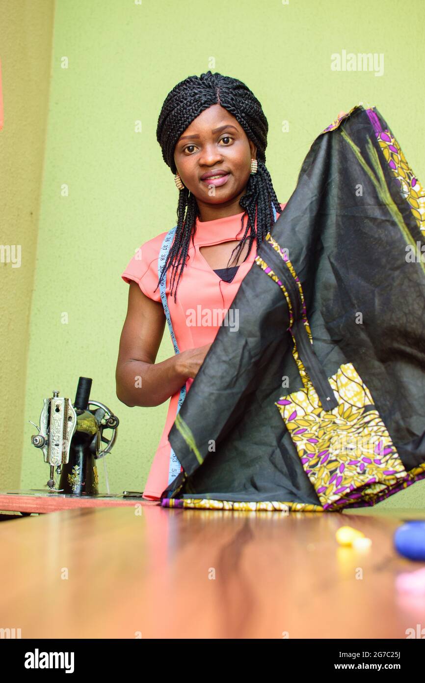 Une femme africaine industrieuse tailleur, designer de mode ou couturière, confectionnée des vêtements élégants et tendance avec machine à coudre dans un travail de couture Banque D'Images