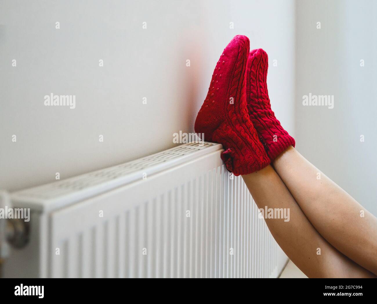Une jeune femme en chaussettes chaudes et confortables réchauffe ses jambes près de la Banque D'Images