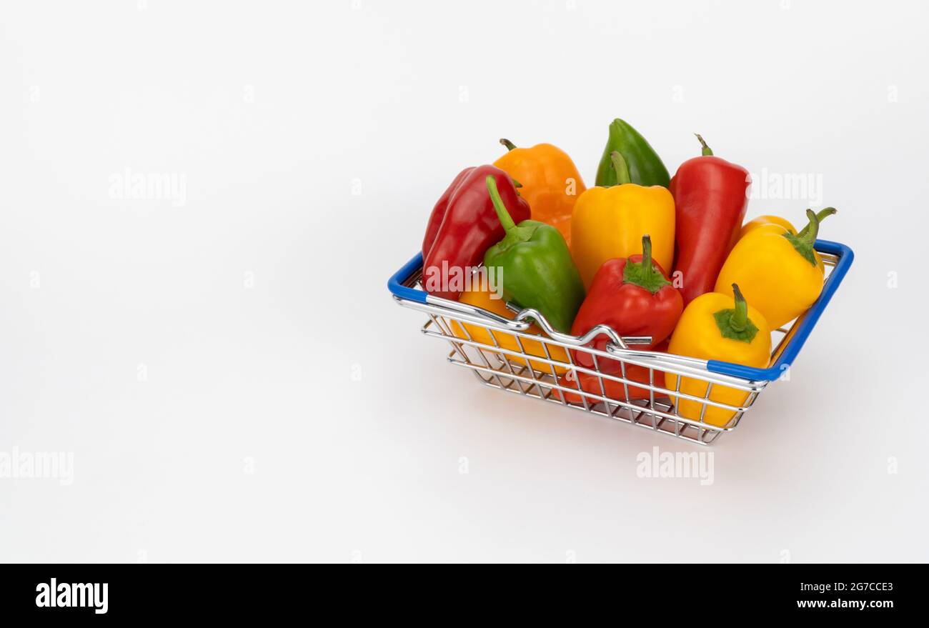 panier d'épicerie miniature rempli de poivrons colorés. panier de supermarché avec paprika. Banque D'Images