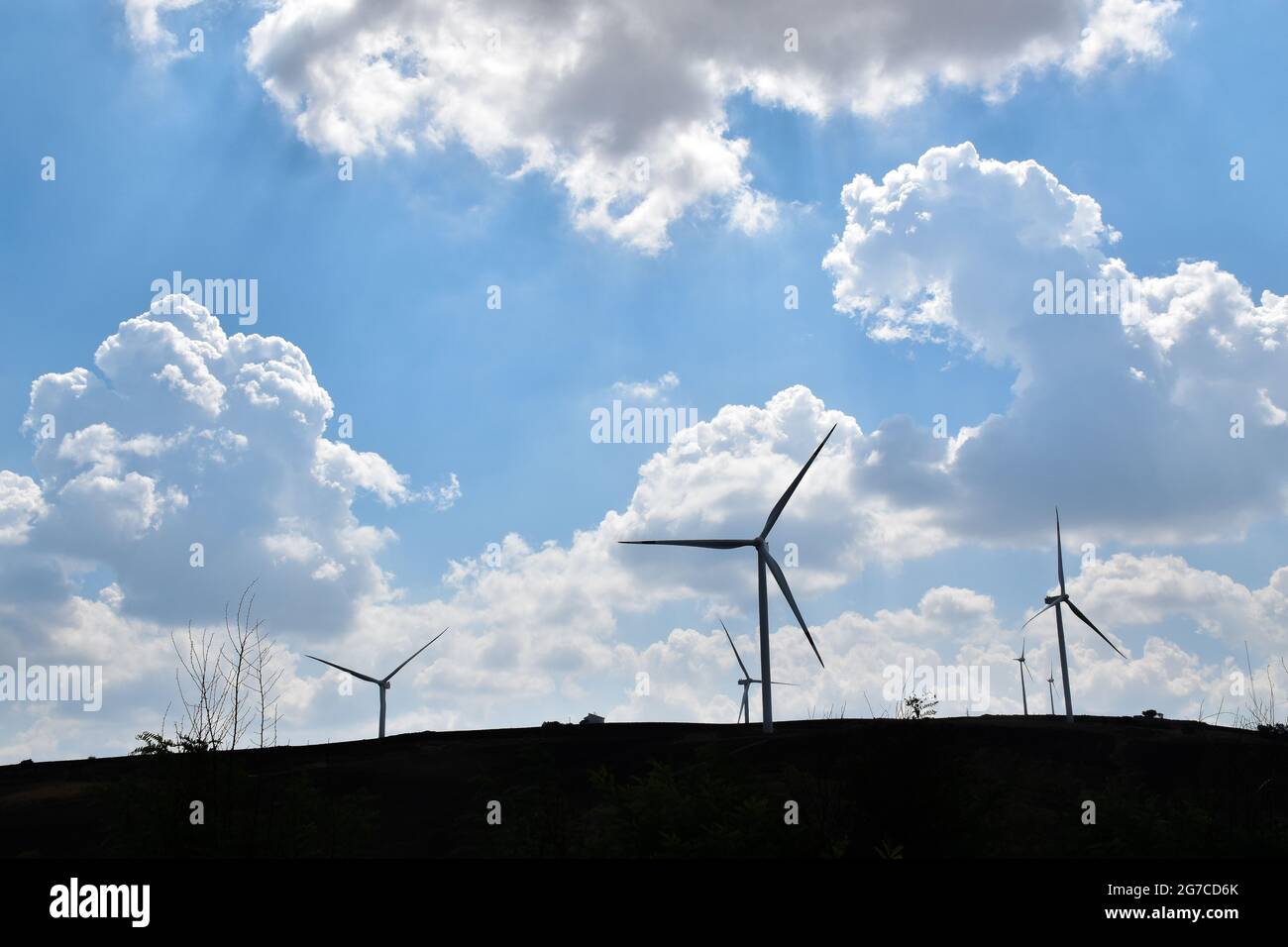 Silhouette d'éoliennes sur une colline avec le fond d'un ciel bleu avec des nuages épars. Banque D'Images